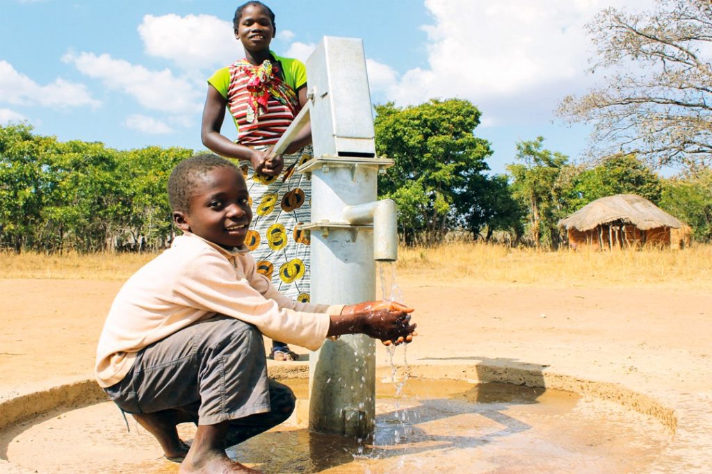 Woman pumping water, boy washing hands