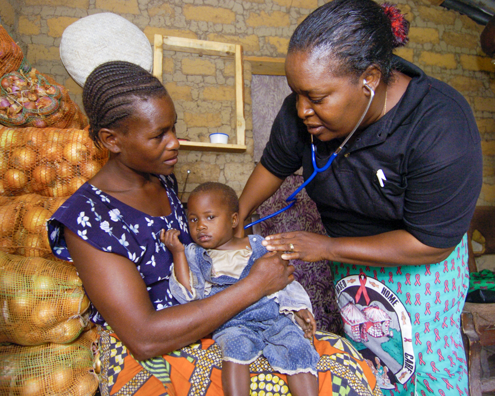 A woman holds her child while a medical professional listens to the child's lungs in Uganda