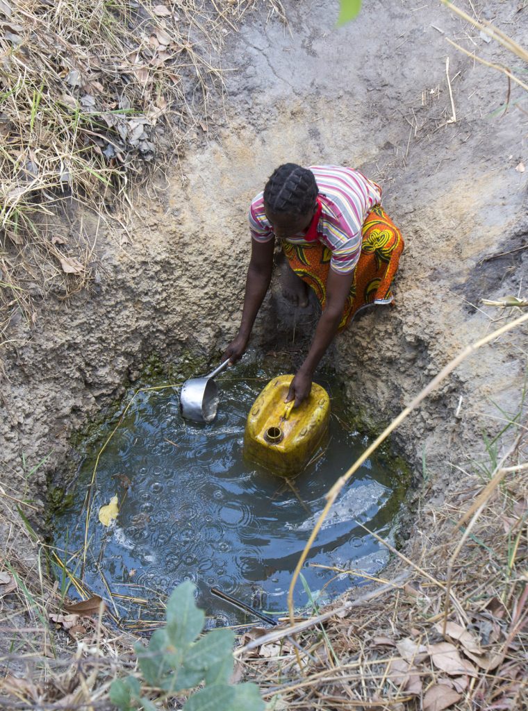 Zambian woman gathering water from a contaminated water hole. The only water source available to their village.