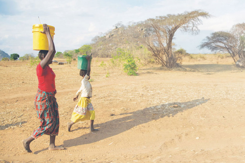 Mother and daughter carrying water, walking through the Kabanga and Milonze villages in Chipata, Zambia.
