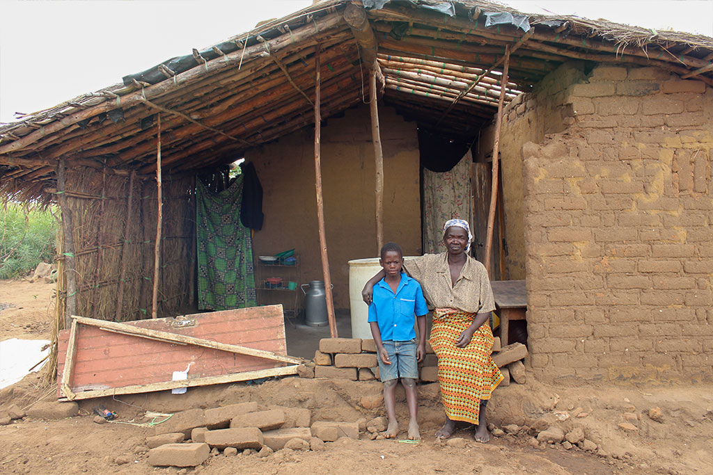 Boy and his grandmother in front of their dilapidated house