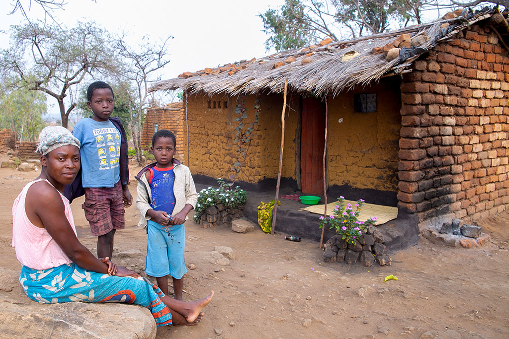 Family in front of their unsafe mud brick house