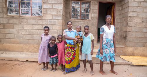 Family standing in front of the home built as part of the housing program in Malawi