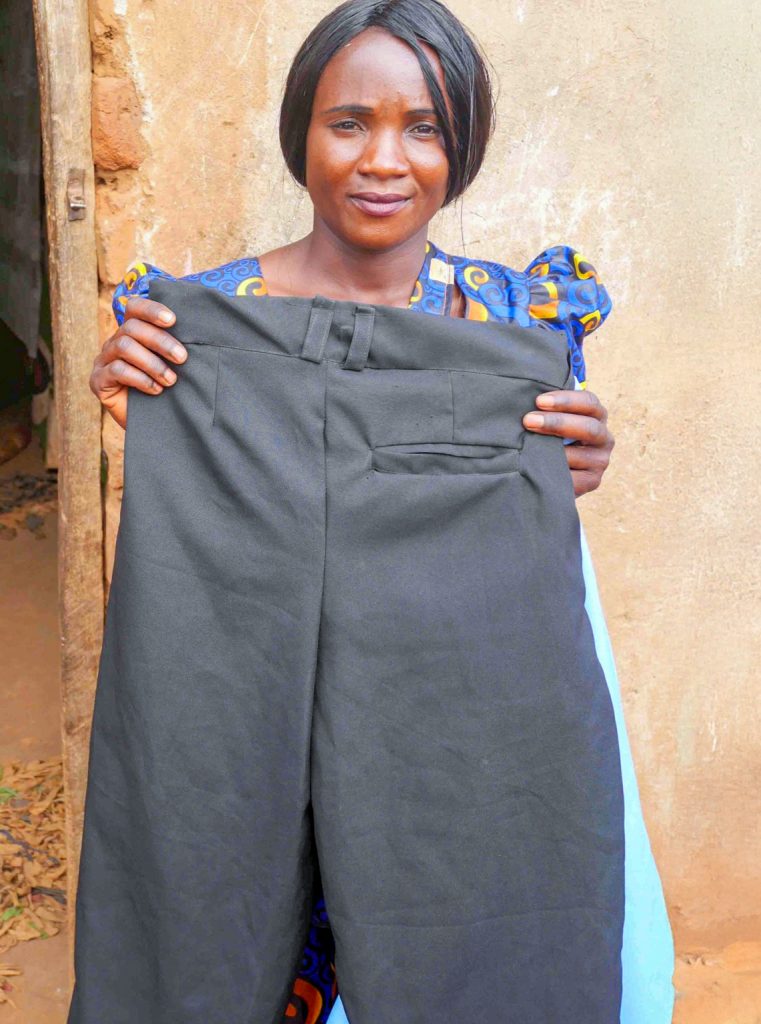 School uniforms are one of Dorika’s primary sources of income. Here she holds up a pair of recently-completed uniform pants, which she will soon deliver to her client.